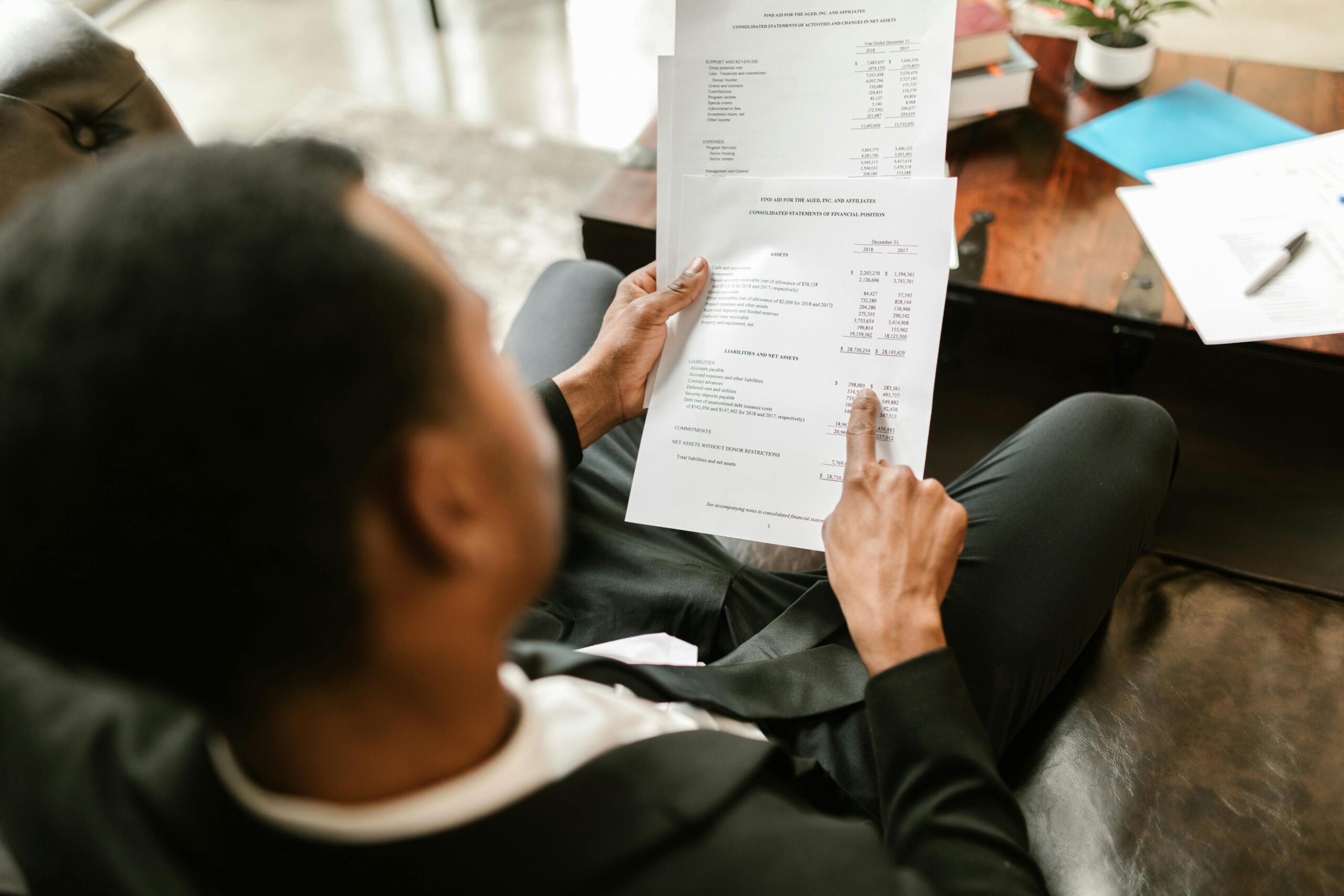 Business professional examining financial documents, focusing on analytics and paperwork in an office setting.